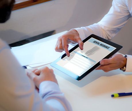 Two people looking at dental insurance on digital pad