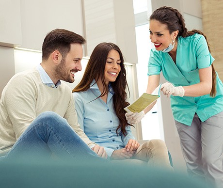 Dental assistant showing smiling couple form