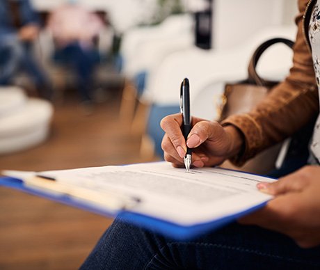 Patient filling out forms on clipboard in lobby