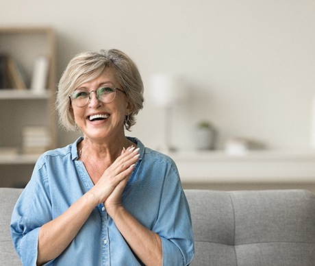 Senior woman with glasses smiling while sitting on couch