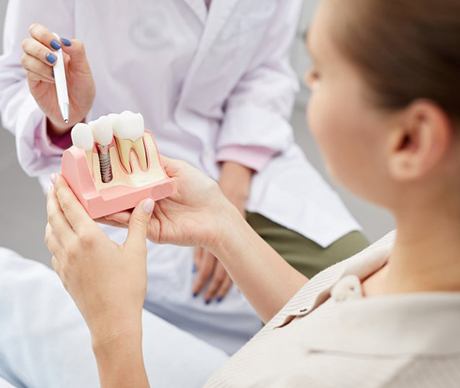 a patient holding a model of a dental implant
