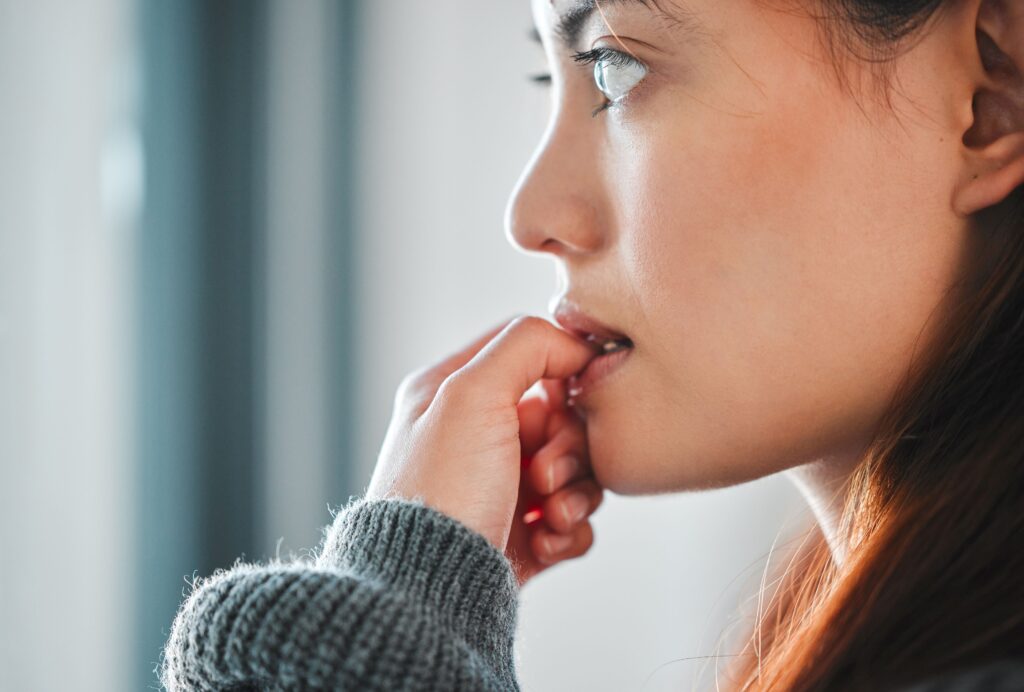 Profile nose-to-chin view of woman nibbling her thumb nail