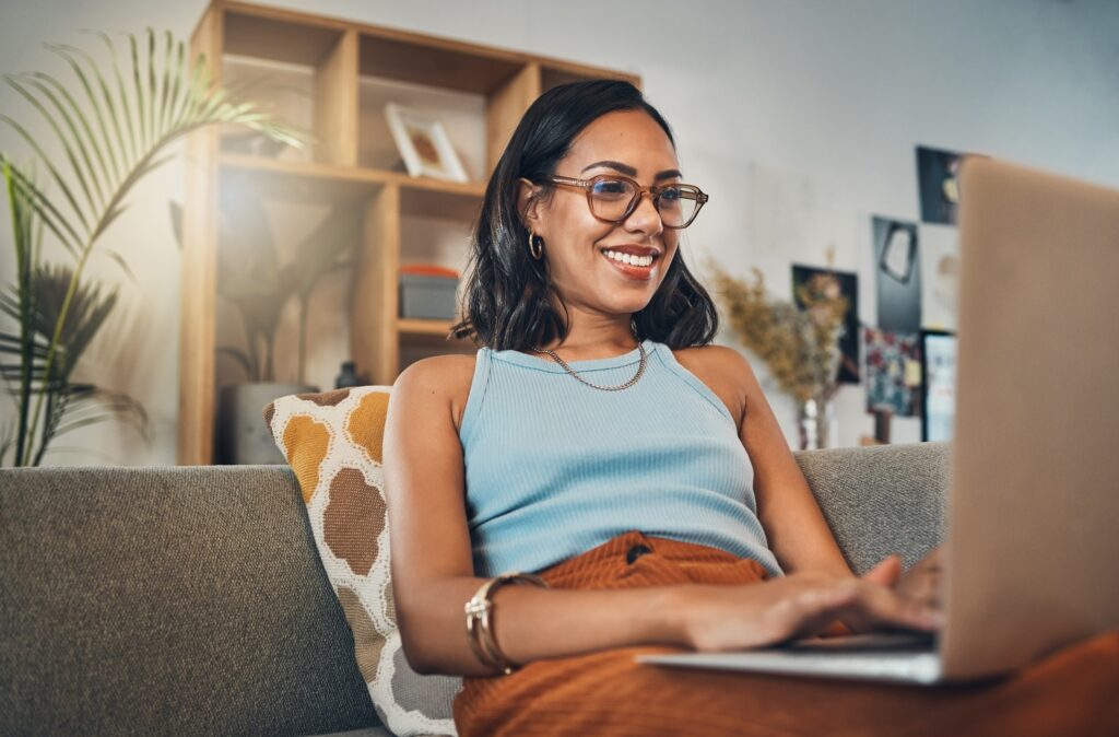 Woman smiling while working on laptop at home